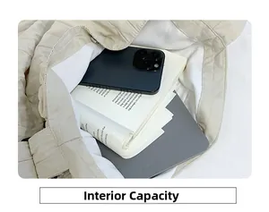Interno della borsa tote in tela trapuntata beige con tablet, telefono e libro