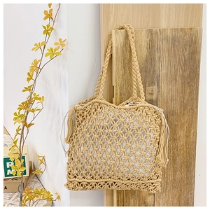 Close-up of handmade cotton macrame tote bag with intricate grid pattern and soft tassels