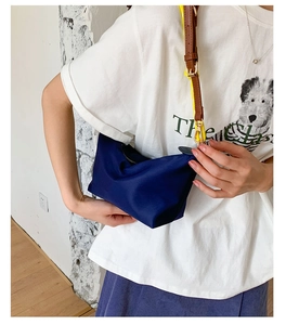 Detail of navy nylon shoulder bag with contrasting brown leather and yellow straps