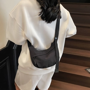 Detailed back view of a black crescent crossbody bag with adjustable strap on a model