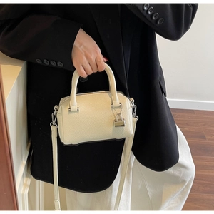 Detail of off-white lychee grain mini boston bag with metal lock and shoulder strap