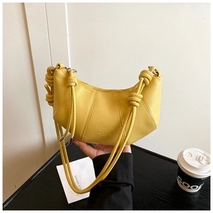 Detail der gelben Sichel-Tasche mit Lychee-Struktur und dem einzigartigen Knotengriff