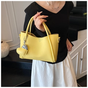 Yellow lychee textured leather tote with heart pendant and adjustable shoulder strap