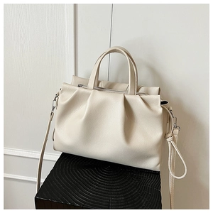 Detail of beige pleated tote bag showing lychee grain leather and metal zipper closure