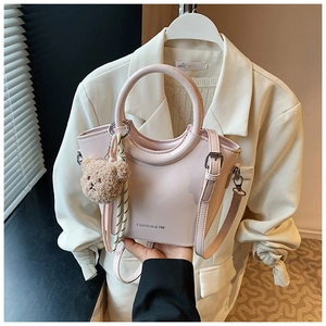 Pink patent leather bucket bag featuring a bear charm and silk scarf handle detail