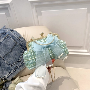Close-up of light blue tweed shell bag with organza bow and pearl charm detailing