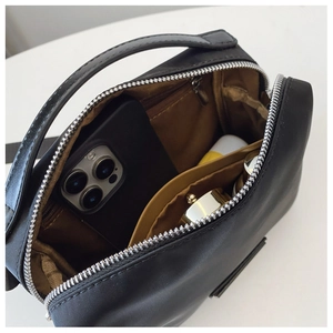 Vue de dessus du sac compact en nylon noir montrant la doublure brune et les compartiments