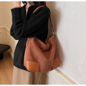 Detailed close-up of brown suede and smooth leather tote bag with white contrast stitching