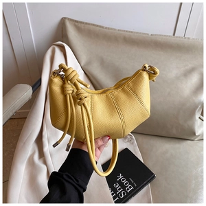 Nahaufnahme der gelben halbmondförmigen Tasche mit Knotengriff und Quasten-Detail