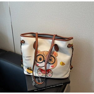 Detailed close-up of a white tote bag featuring a cute bear embroidery and brown handles