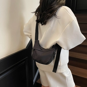 Detailed view of the black nylon crescent bag with wide adjustable strap worn by model