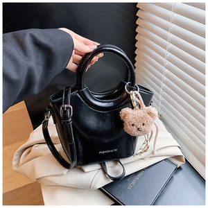 Detail of black bucket bag with round handle, silver hardware and cute bear charm