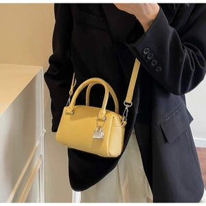 Close-up of yellow lychee texture mini Boston bag with silver lock and long strap