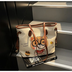 Close-up of a cream tote bag featuring cute bear prints and brown lychee texture handles