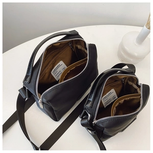 Vue de dessus des compartiments zippés et de la bandoulière réglable du sac en nylon noir