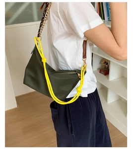 Detail of dark green shoulder bag with yellow woven strap and gold chain link