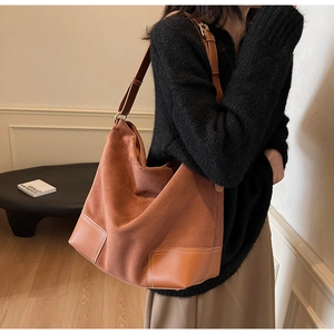 Detail of caramel suede hobo bag with contrast stitching and adjustable strap on model