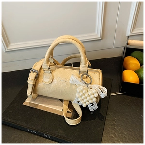 Detail of a creamy yellow cylinder handbag with wrinkled leather and a heart pearl charm