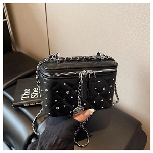 Detail of a black quilted vanity bag with sparkling rhinestones and flower pendant charm
