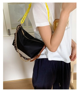 Detail of black nylon shoulder bag featuring yellow rope handle and gold chain strap
