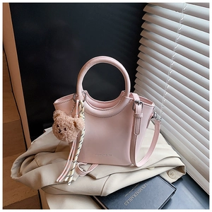 Pink bucket bag with round handle featuring a brown teddy bear charm and striped scarf