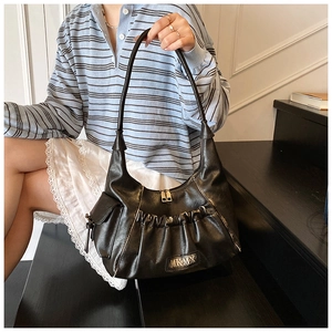 Detail of black pleated baguette bag with MKMX metal logo and smooth zipper closure
