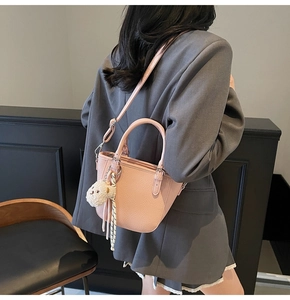 Detail showing pink pebble leather handbag worn over shoulder with teddy bear charm