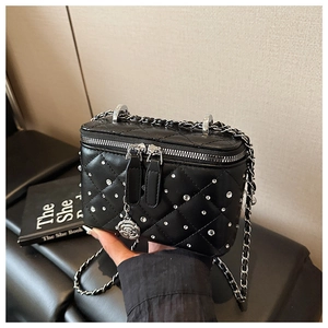 Close-up of quilted black mini bag with rhinestone accents and floral metal pendant