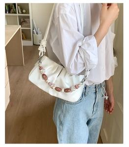 Detail of white pleated cloud bag with marble bead chain and slim shoulder strap