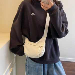 Detail view of off-white crescent crossbody bag with wide strap and zipper pockets