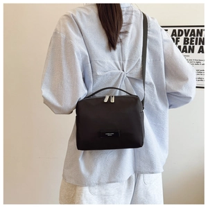 Détail du sac bandoulière en nylon noir avec zip argenté et poignée robuste
