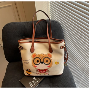 Close-up of large beige tote bag with cute bear print on a stylish corduroy chair