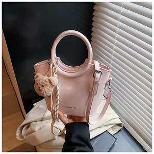 Dettaglio borsa a secchiello rosa con ciondolo a orsetto e foulard in seta sul manico