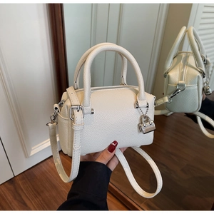 Detailed shot of white pebbled leather pillow bag with silver lock and handles