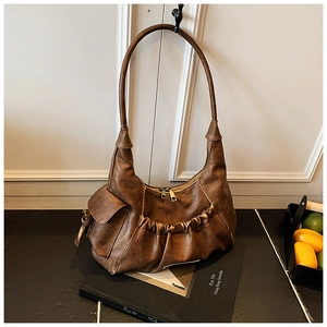 Detail of vintage brown pleated hobo bag showing gathered leather texture and side pocket
