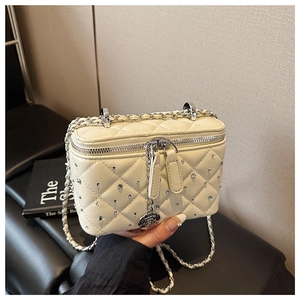 Detail of cream quilted crossbody bag with silver studs and rose pendant