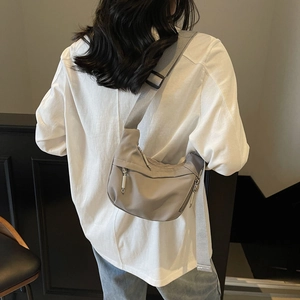 Detail of adjustable grey nylon strap and zipper compartments on the crossbody bag