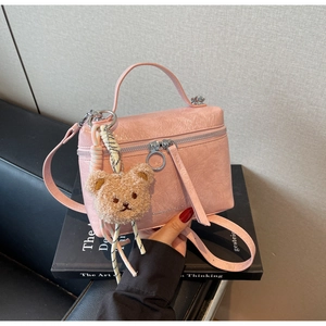 Detailed view of pink textured bucket bag featuring a cute bear charm and silver hardware