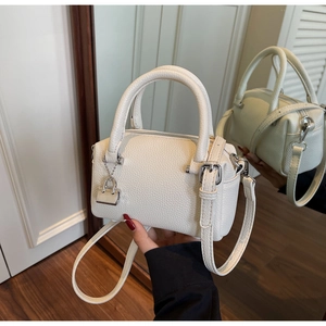Detail of white lychee pattern Boston bag with silver metal lock and textured leather