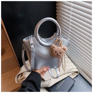 Silver metallic bucket bag detail with round handle and plush bear charm decoration
