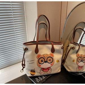 Detail of cream tote bag with bear print and brown straps reflected in a mirror