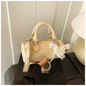 Close-up of cream mini Boston bag with retro wrinkled texture and pearl heart charm