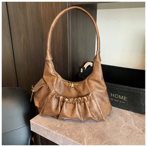 Detailed view of brown vintage pleated baguette bag with textured leather and gold hardware