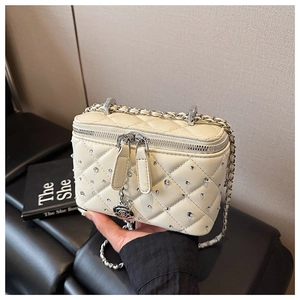 Close-up of quilted beige box bag featuring sparkling rhinestones and flower zipper pull