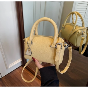 Detail view of yellow lychee grain leather pillow bag with silver lock and mirror reflection