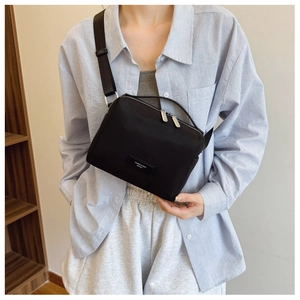 Détail du sac bandoulière en nylon noir avec double fermeture éclair et écusson brodé