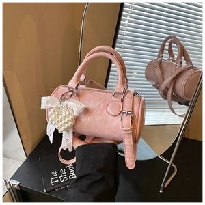 Pink cylinder handbag with pleated texture featuring pearl heart charm and lace bow detail