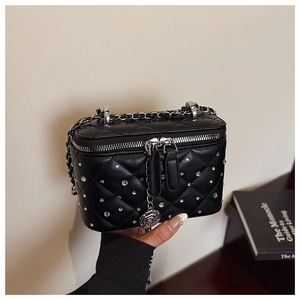 Close-up of black quilted box bag with sparkling rhinestones and camellia flower zipper charm