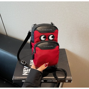 Detail of red and black canvas crossbody phone bag featuring embroidered big eyes and logo