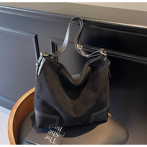 Detail of minimalist black tote bag featuring contrast stitching on suede and leather